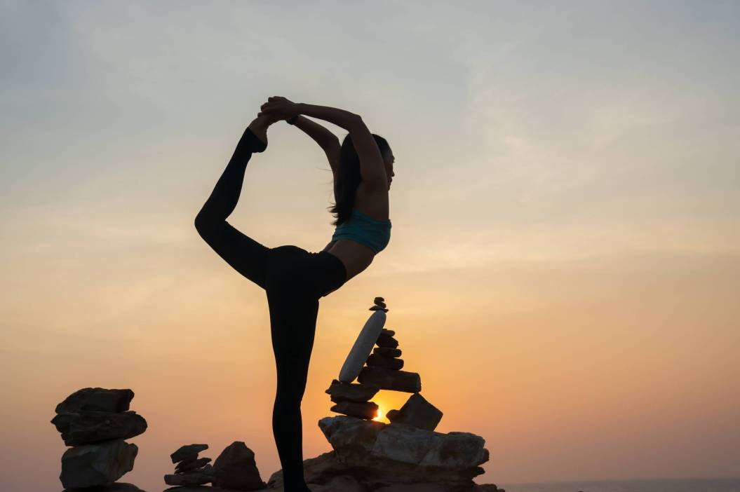 silhouette of Asian woman practicing yoga on the ocean coast wit